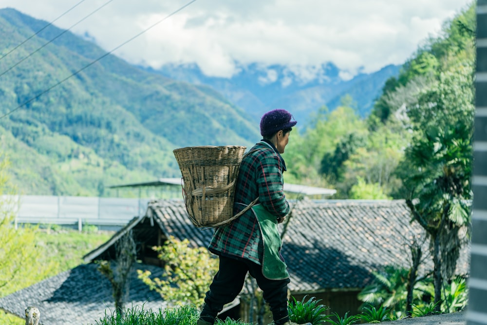 man in brown and black plaid dress shirt and black pants carrying brown woven basket