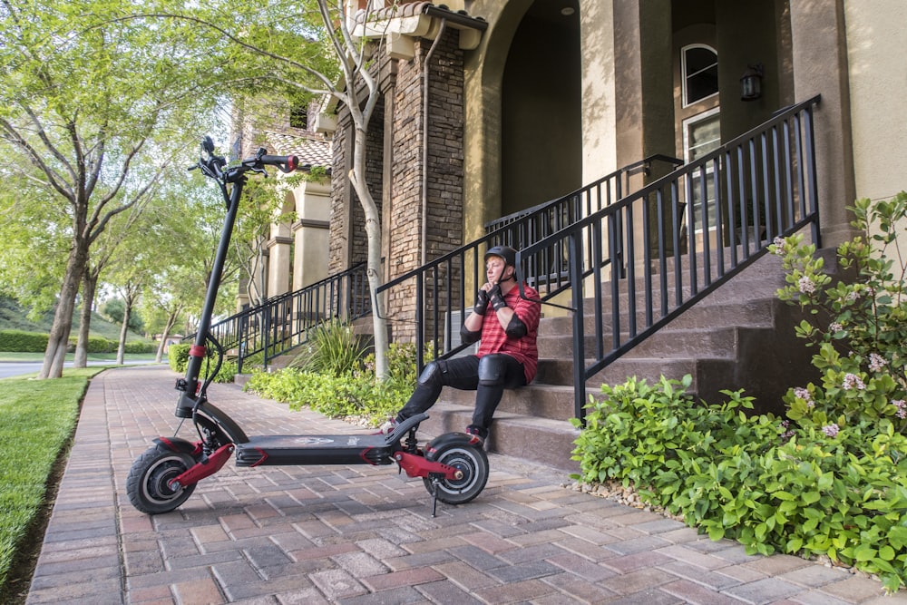 girl in pink jacket riding on red and black kick scooter during daytime