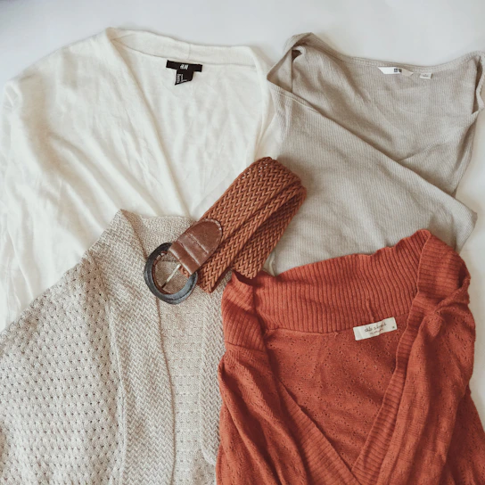 A cozy, minimalist outfit laid out on a light wooden floor, featuring soft neutral tones and natural fabrics.