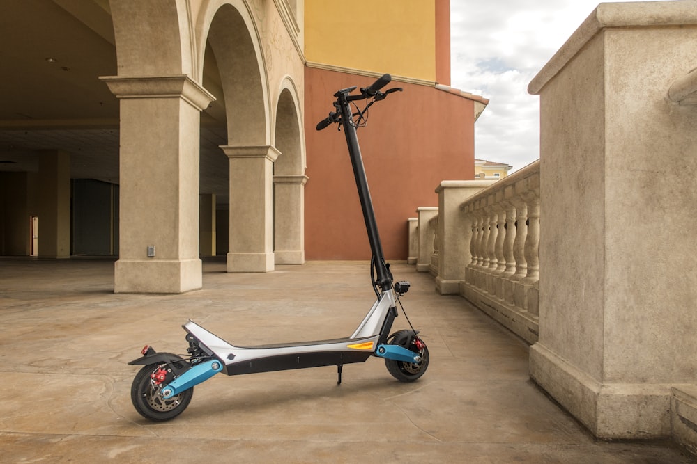 blue and black motor scooter parked beside brown concrete building during daytime