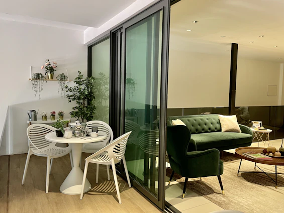 A bright, airy living room showcasing modern Indian decor with elegant furniture and vibrant plants.