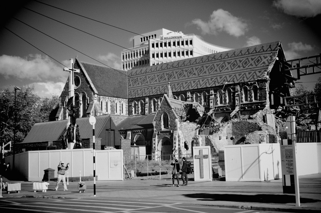 grayscale photo of people walking on street near building