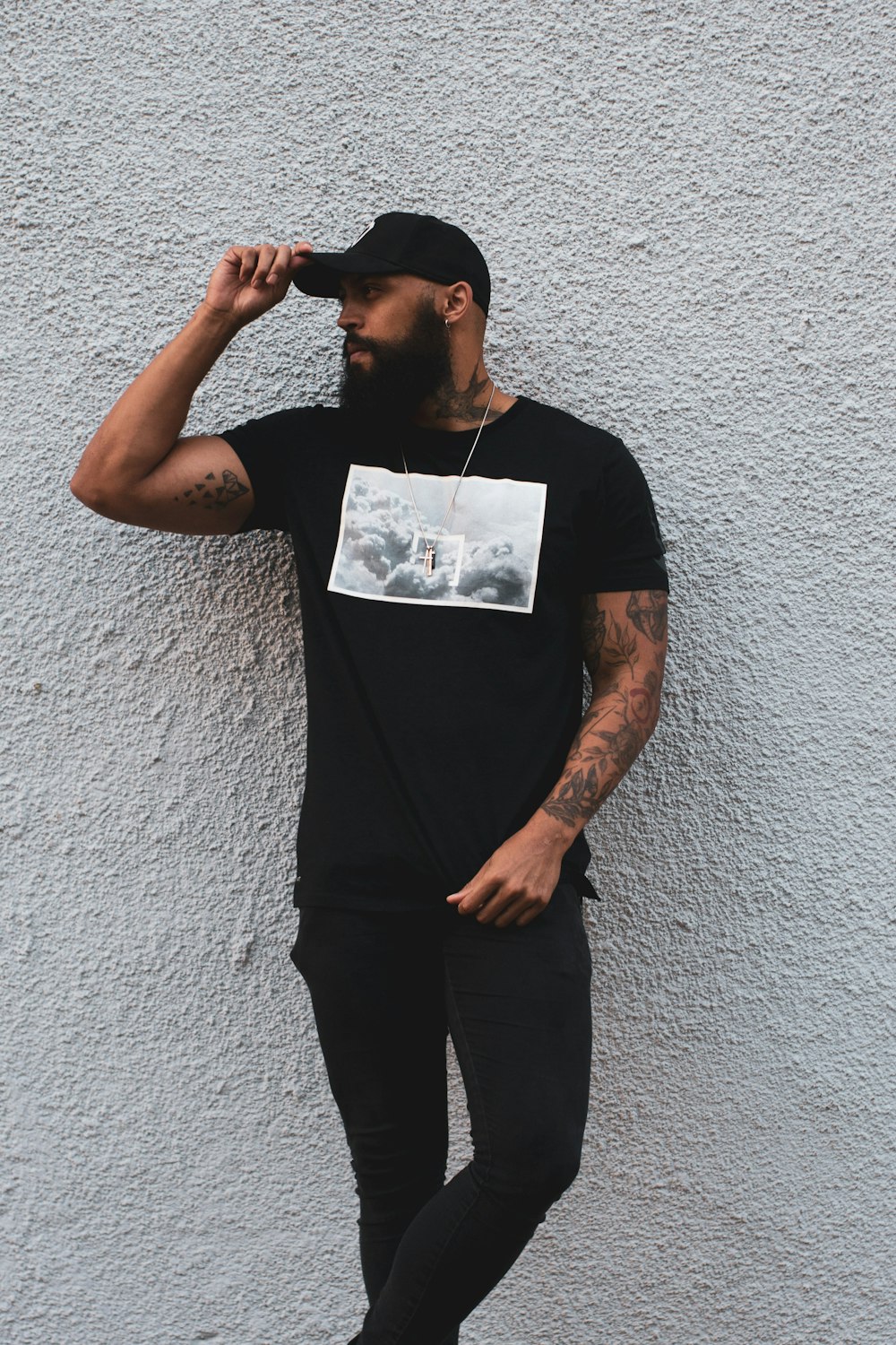 man in black crew neck t-shirt and black pants standing beside white wall