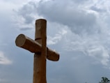 A minimalist cross silhouette against a calm, cloudy sky.