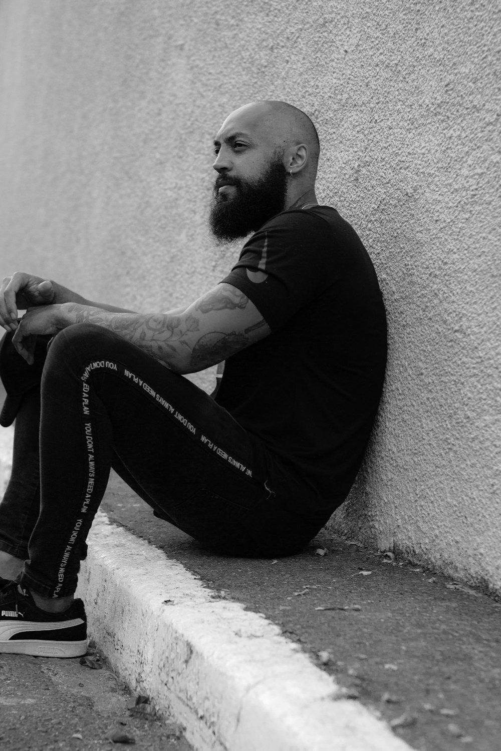 man in black long sleeve shirt and black denim jeans sitting on concrete floor