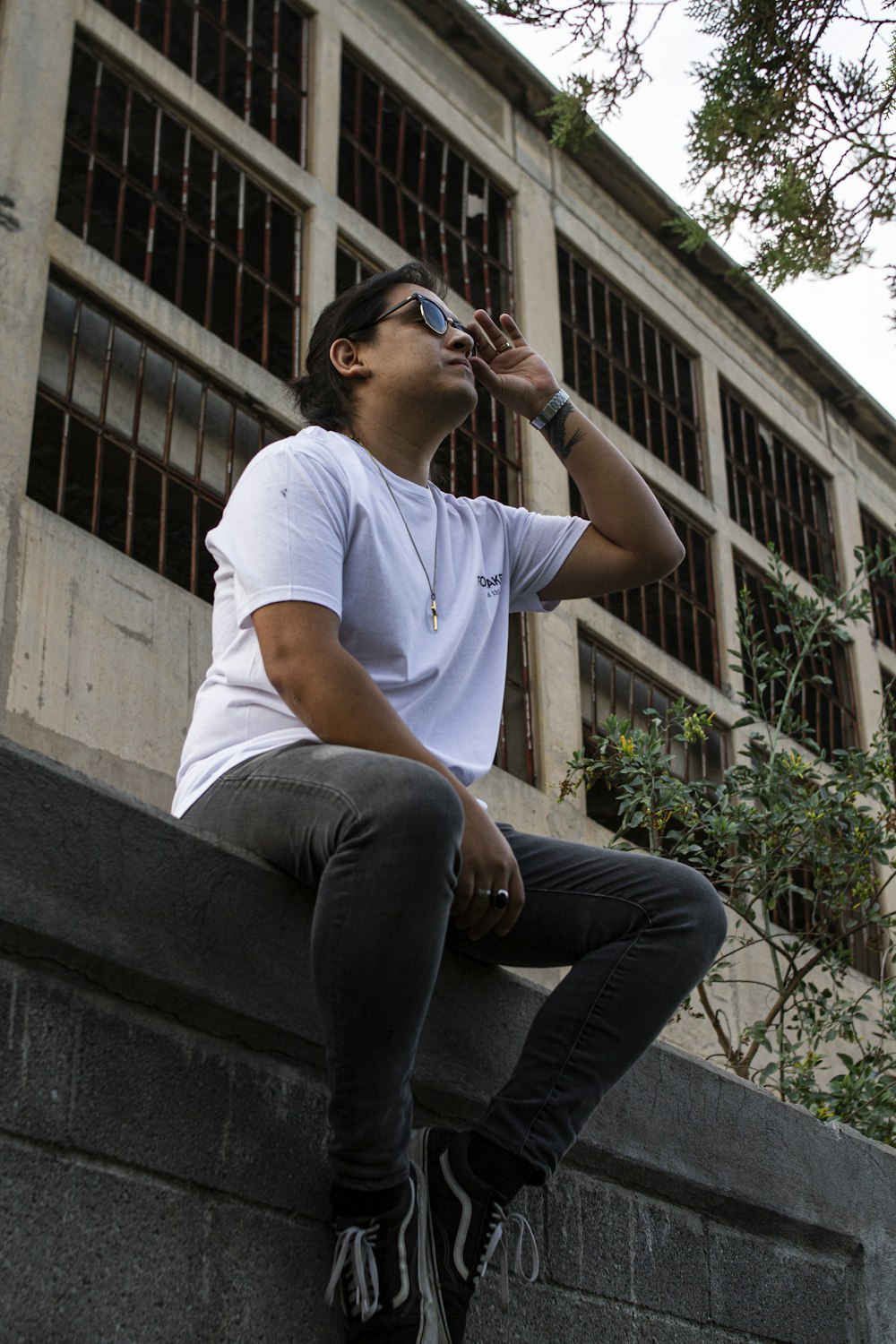 a man sitting on a ledge drinking from a bottle