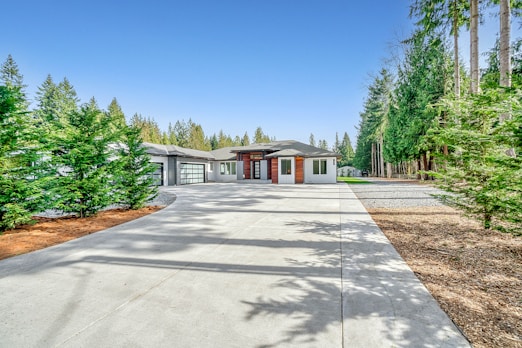 white concrete house near green trees under blue sky during daytime