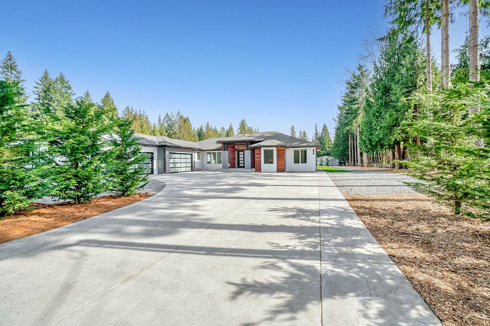 white concrete house near green trees under blue sky during daytime