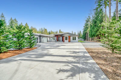 white concrete house near green trees under blue sky during daytime