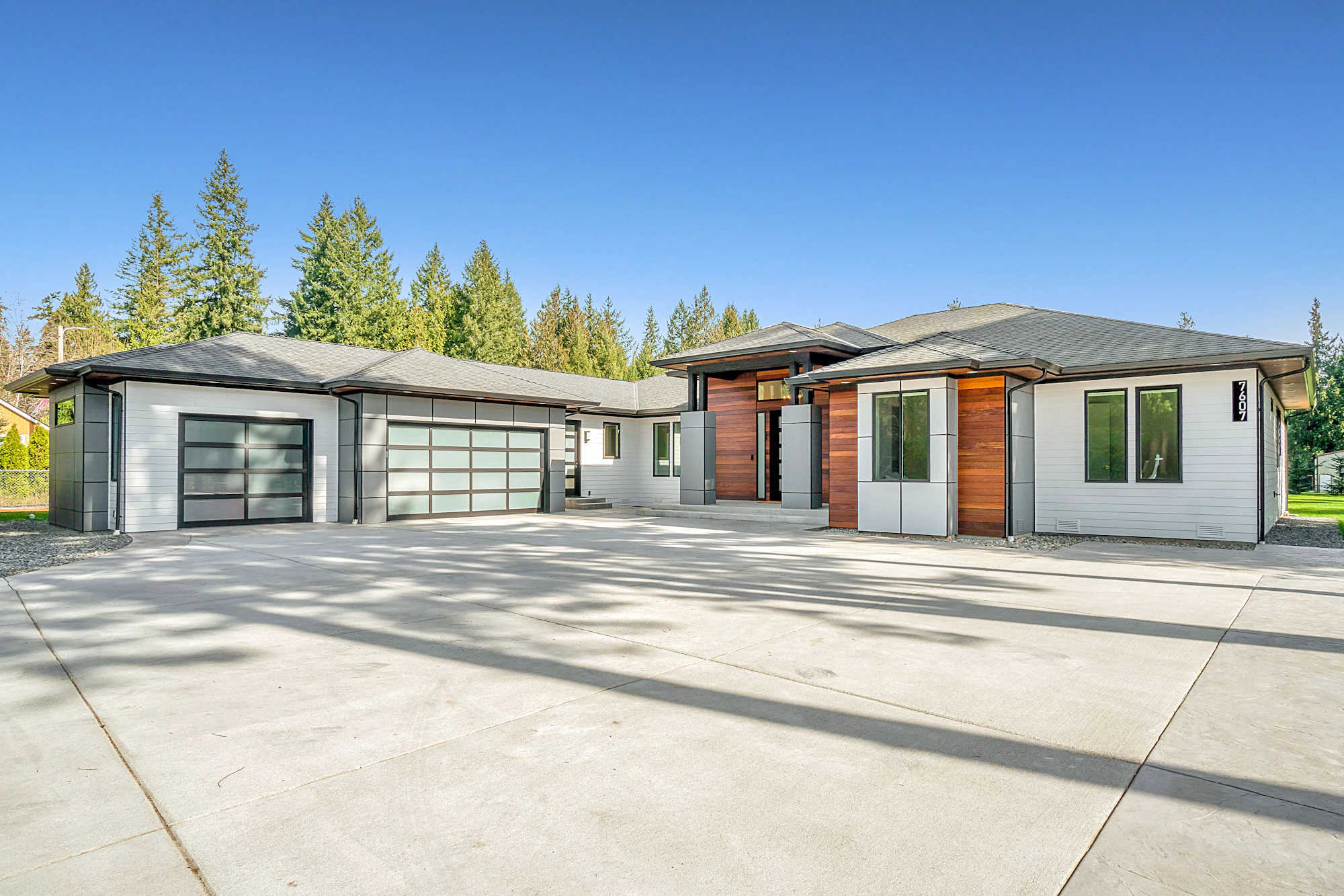 A white and timber clad house set among mature green trees