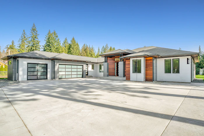 A white and timber clad house set among mature green trees