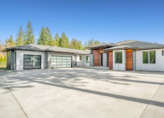 white and brown wooden house near green trees under blue sky during daytime