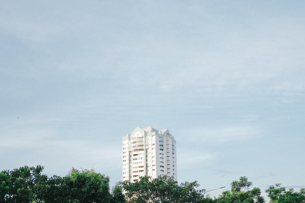 white concrete building near green trees under white sky during daytime
