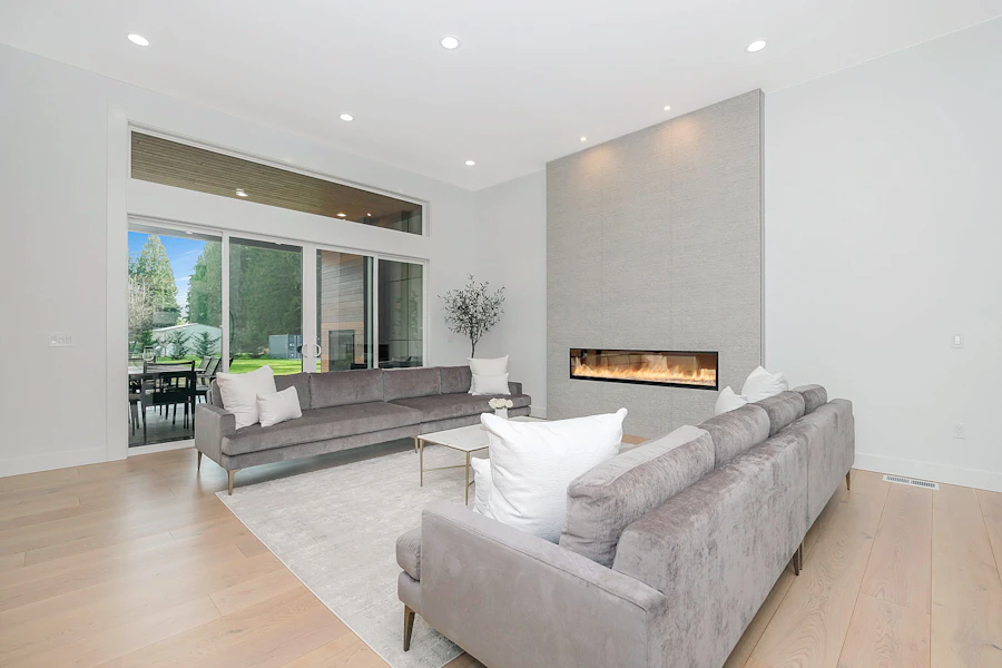 Living room with a grey sofa, tall potted plant and softly painted neutral walls
