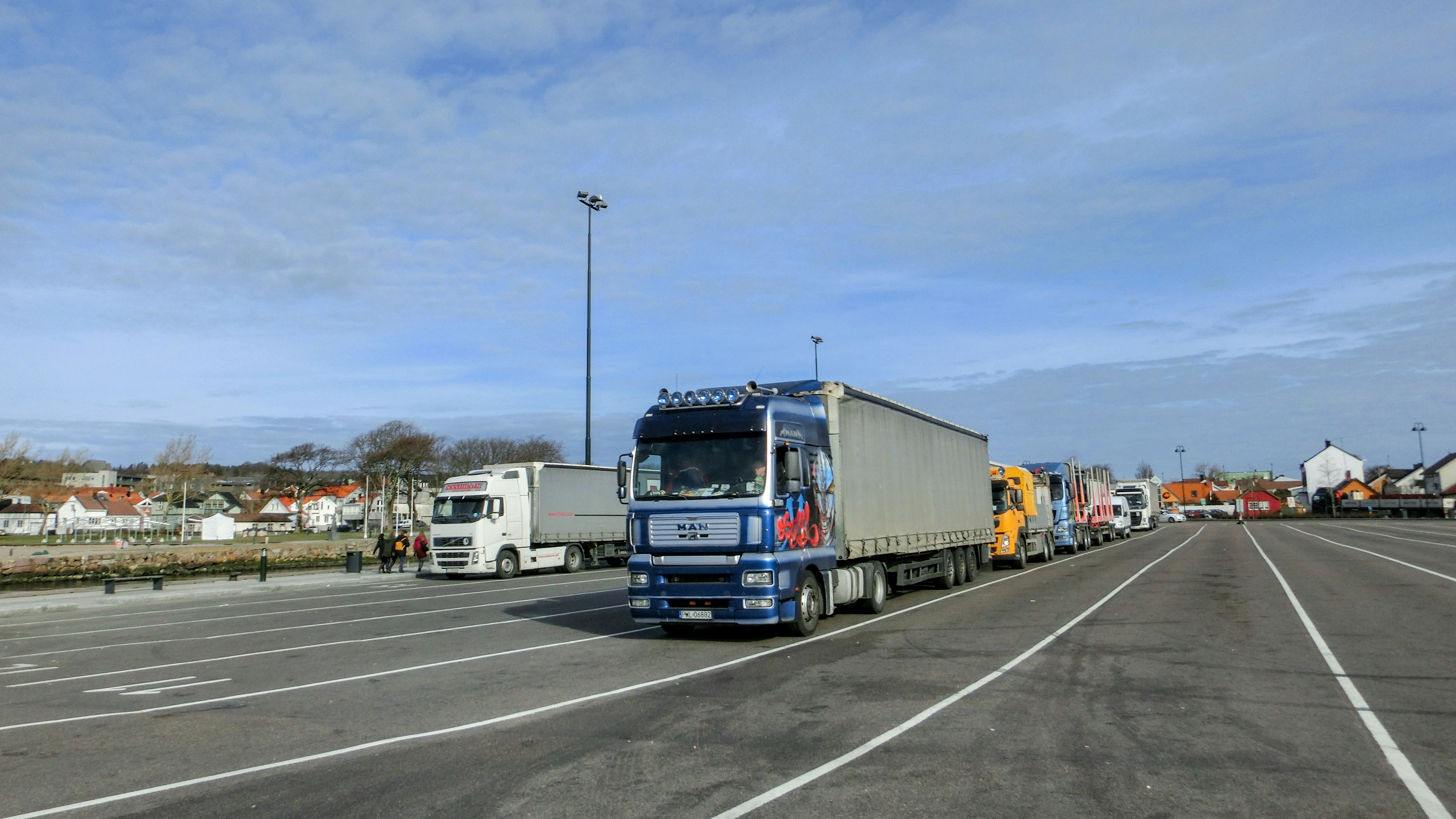 Fleet of heavy-duty semi-trucks lined up in industrial yard, overcast sky, wide angle shot