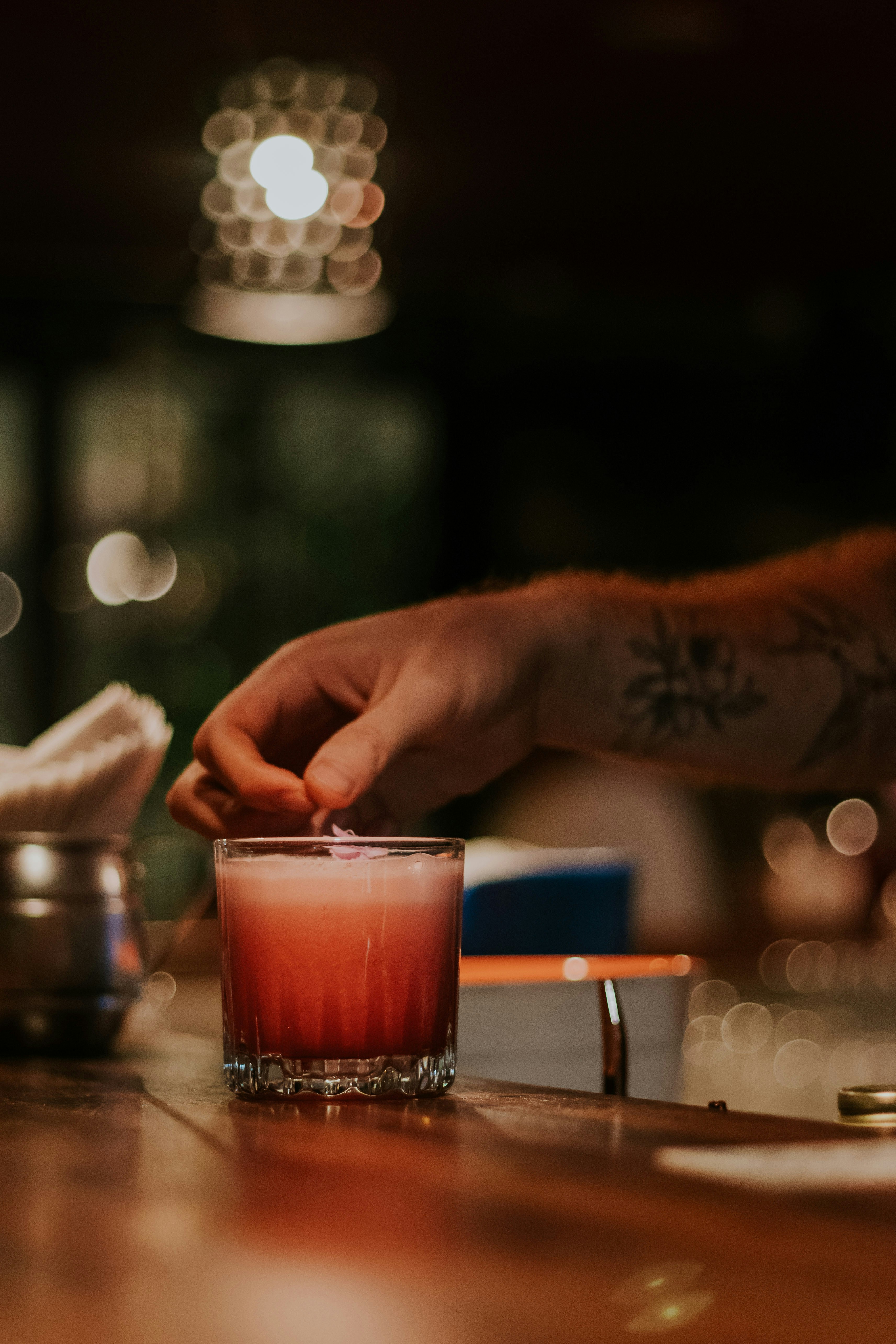 person holding clear drinking glass with red liquid
