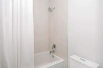 A sleek, modern shower system installed in a minimalist luxury bathroom with soft natural lighting.