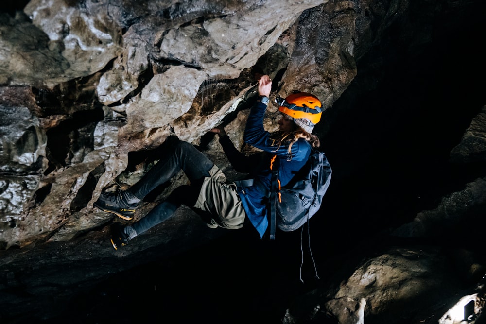 man in blue jacket and black pants sitting on rock