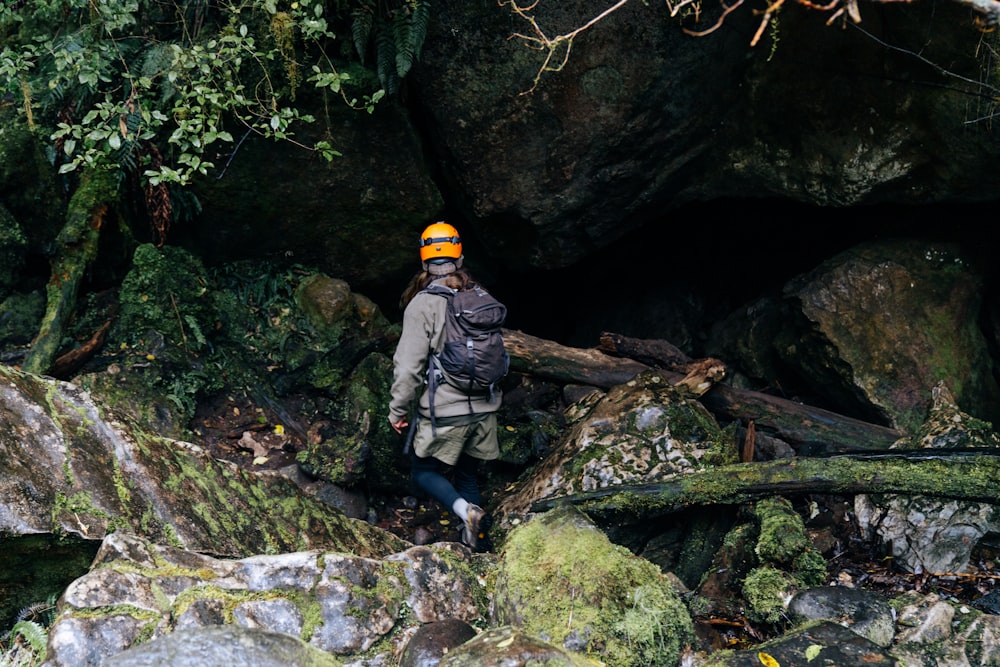 man in gray jacket and yellow helmet standing on rocky river during daytime