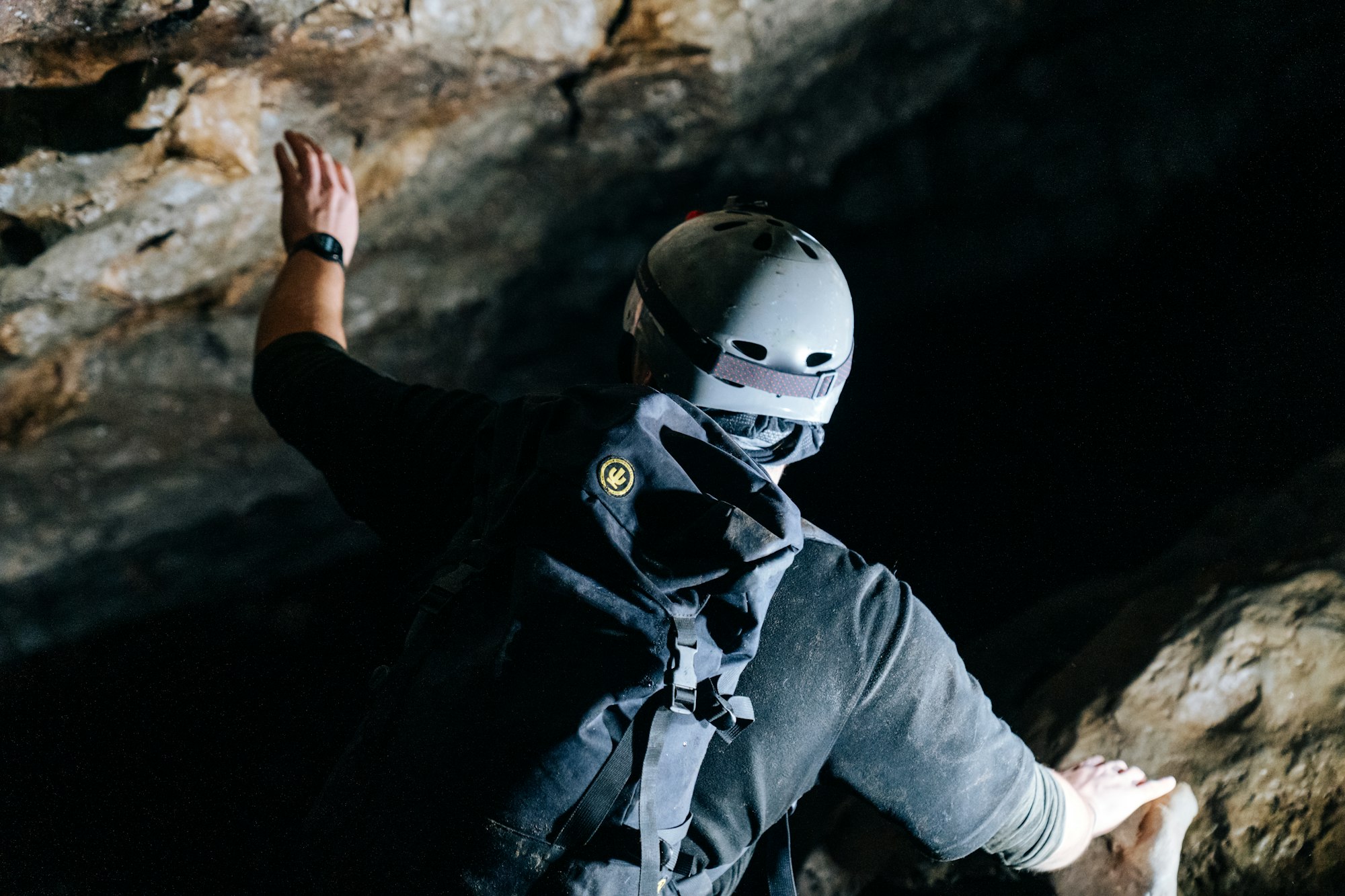 Man wearing helmet and backpack exploring cave