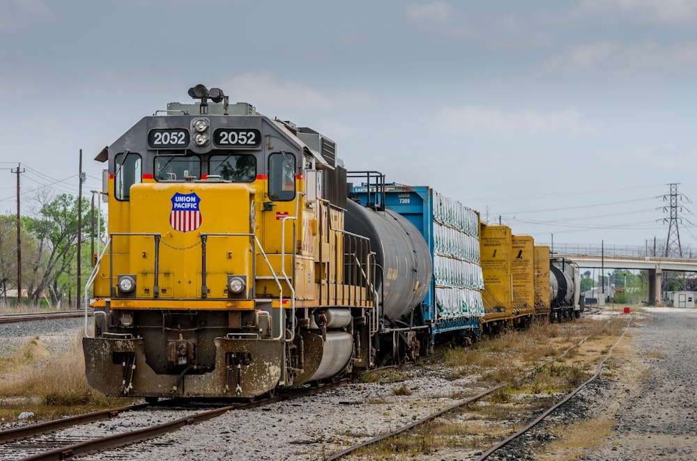 yellow blue and black train on rail tracks during daytime