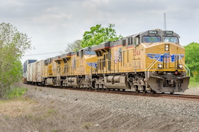 yellow and green train on rail tracks during daytime