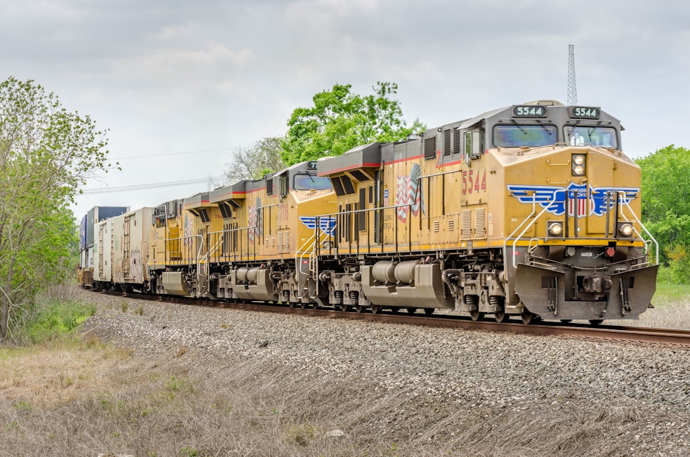 yellow and green train on rail tracks during daytime