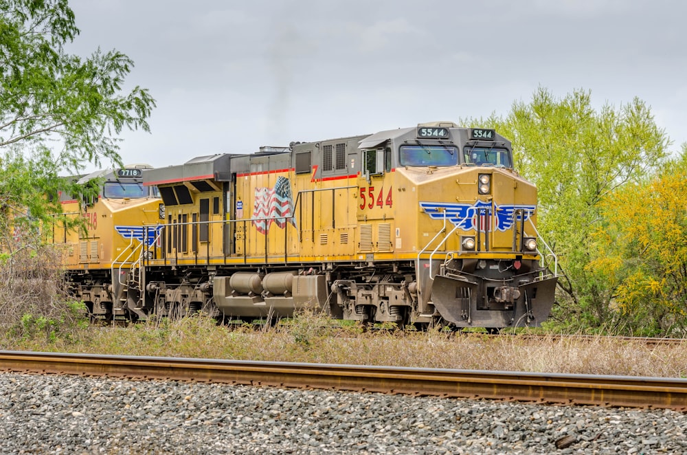 Treno giallo e rosso sui binari ferroviari sotto nuvole bianche durante il giorno