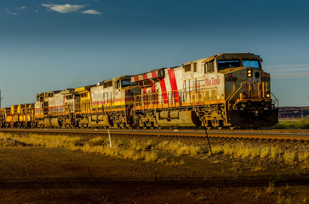 red yellow and blue train on rail tracks during daytime