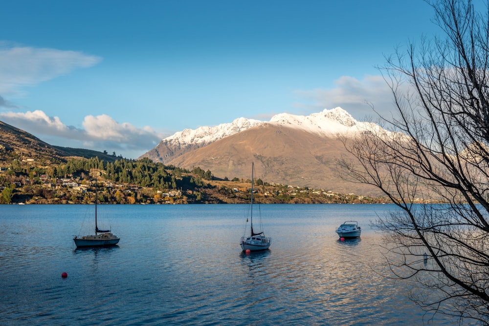 white and black boat on body of water near snow covered mountain during daytime