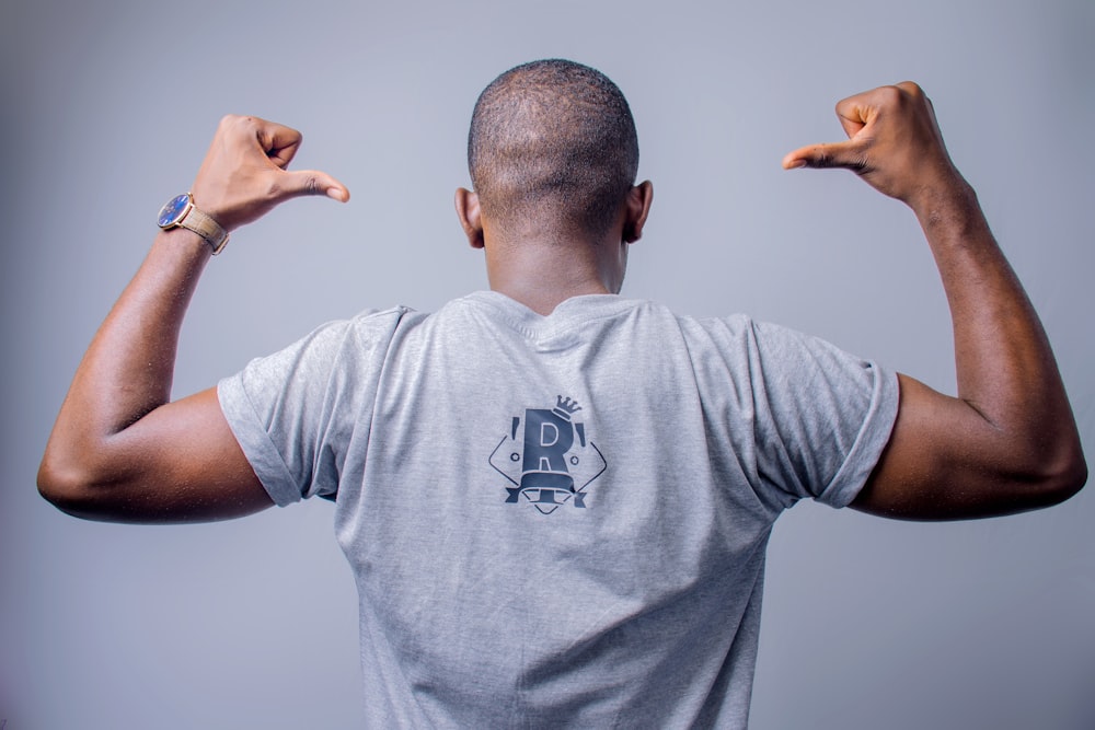 man in gray crew neck t-shirt raising his hands