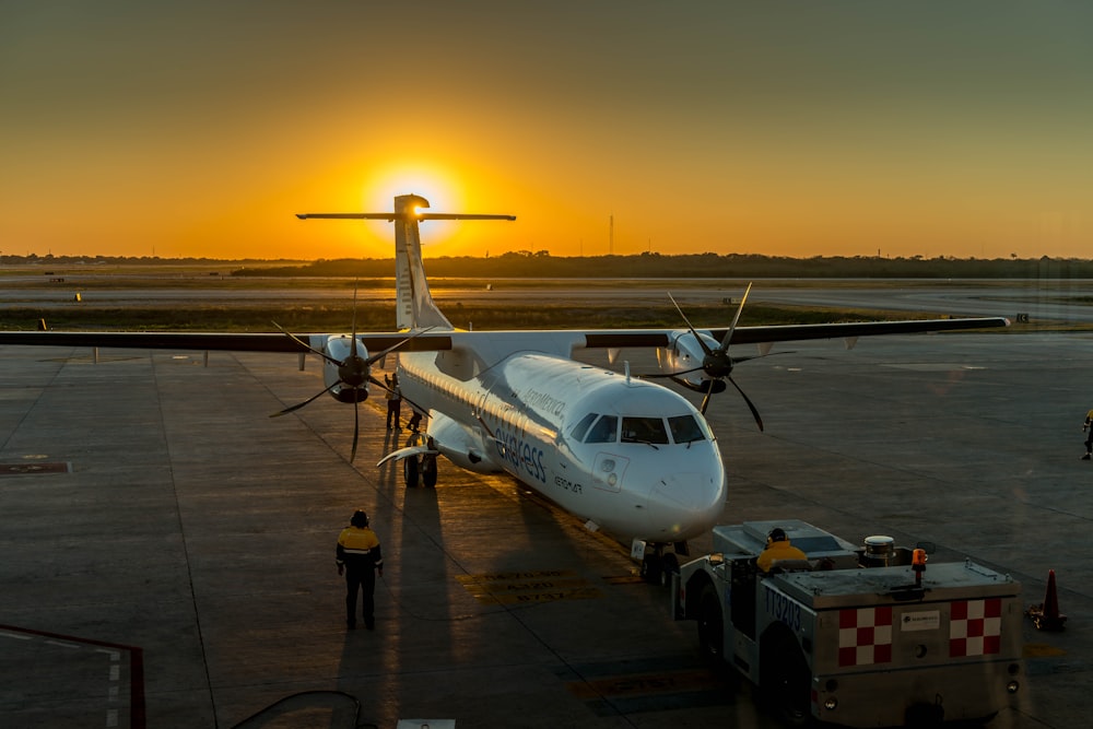 Avión de pasajeros blanco en el aeropuerto durante la puesta del sol