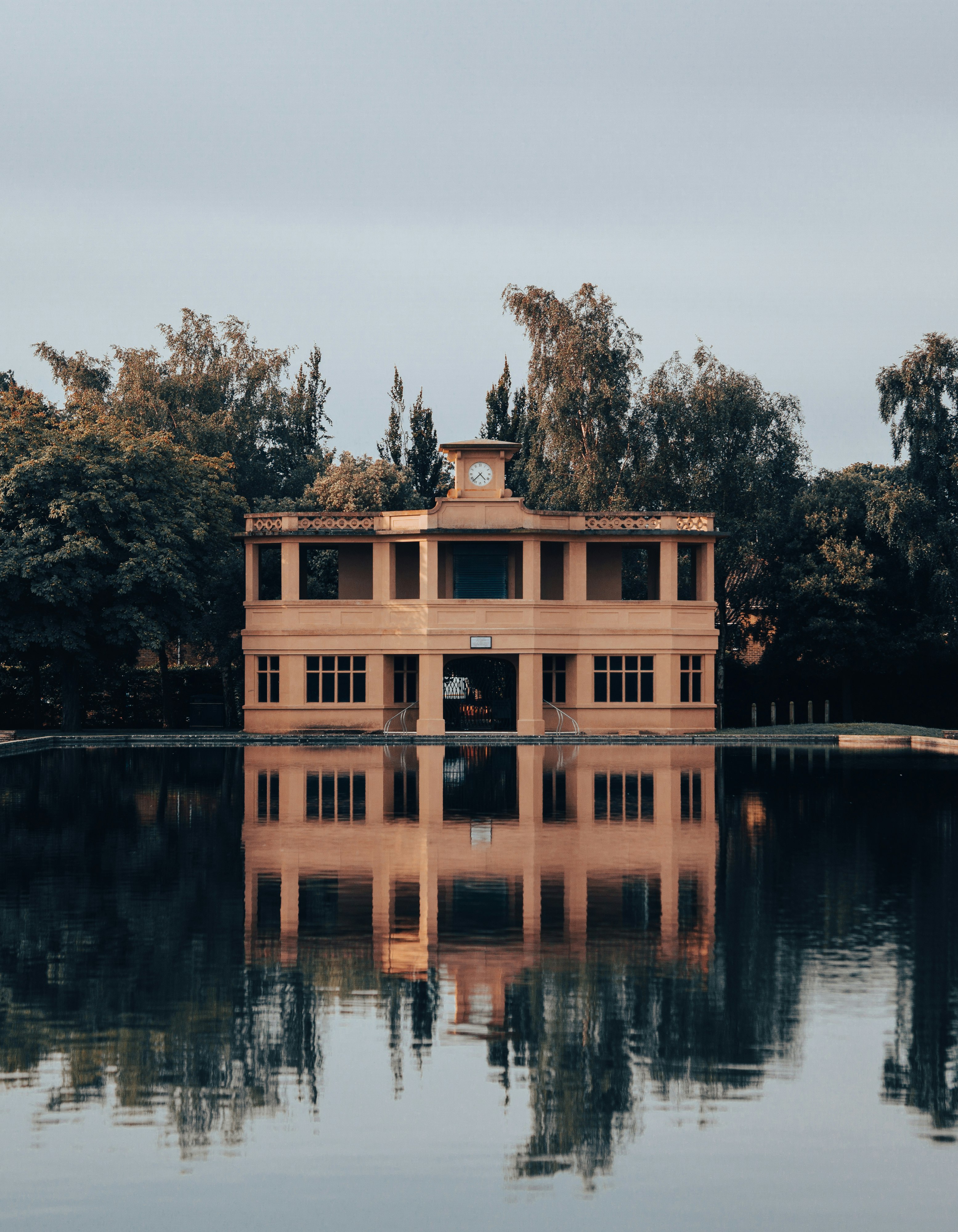 brown concrete building near green trees and lake during daytime