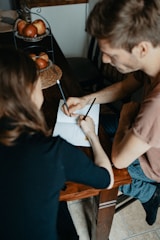 man in brown t-shirt writing on white paper