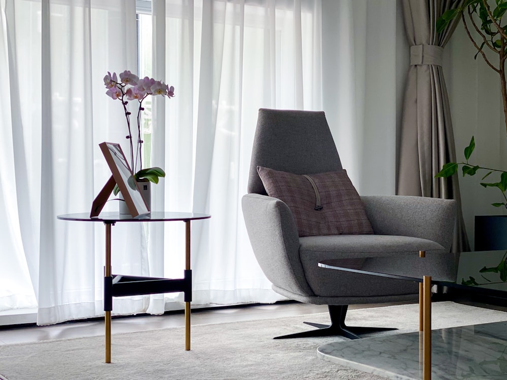 gray and black armchair beside white window curtain