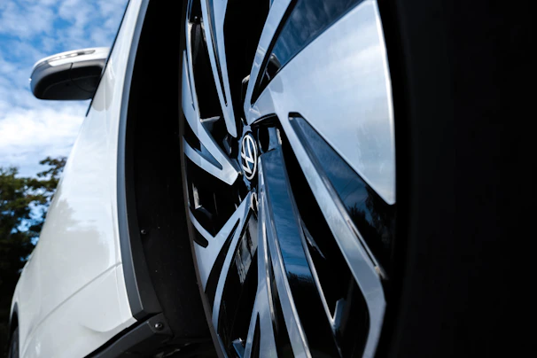 A close-up of a car’s shiny wheel and side mirror reflecting the Canadian landscape.