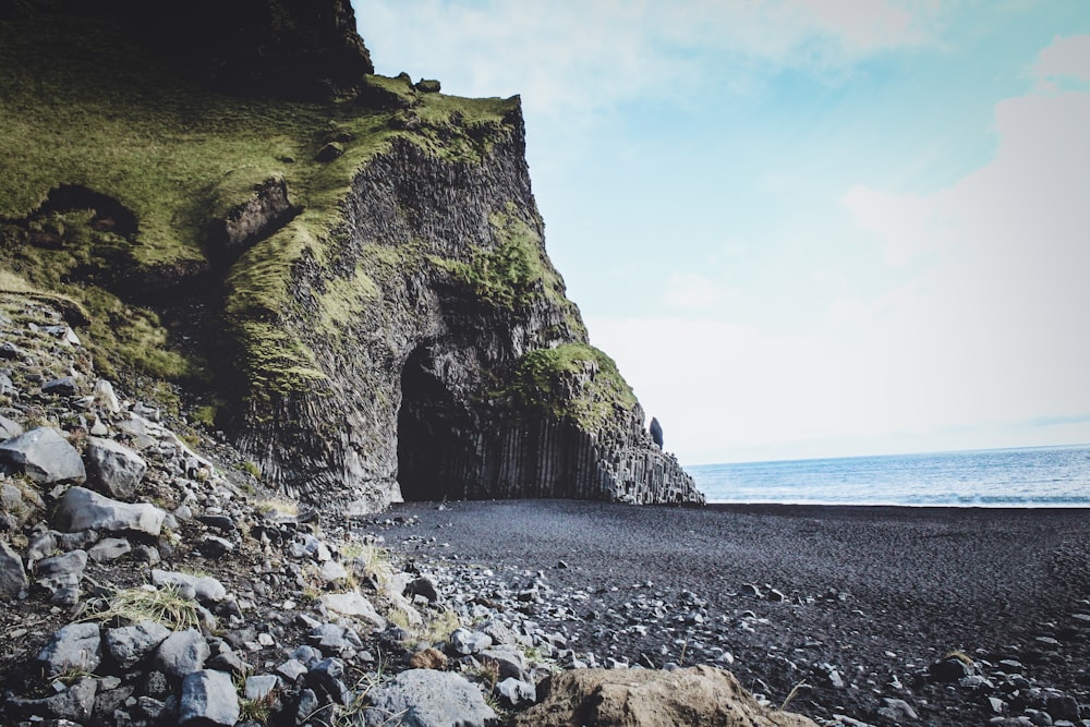 green and brown rock formation on sea shore during daytime