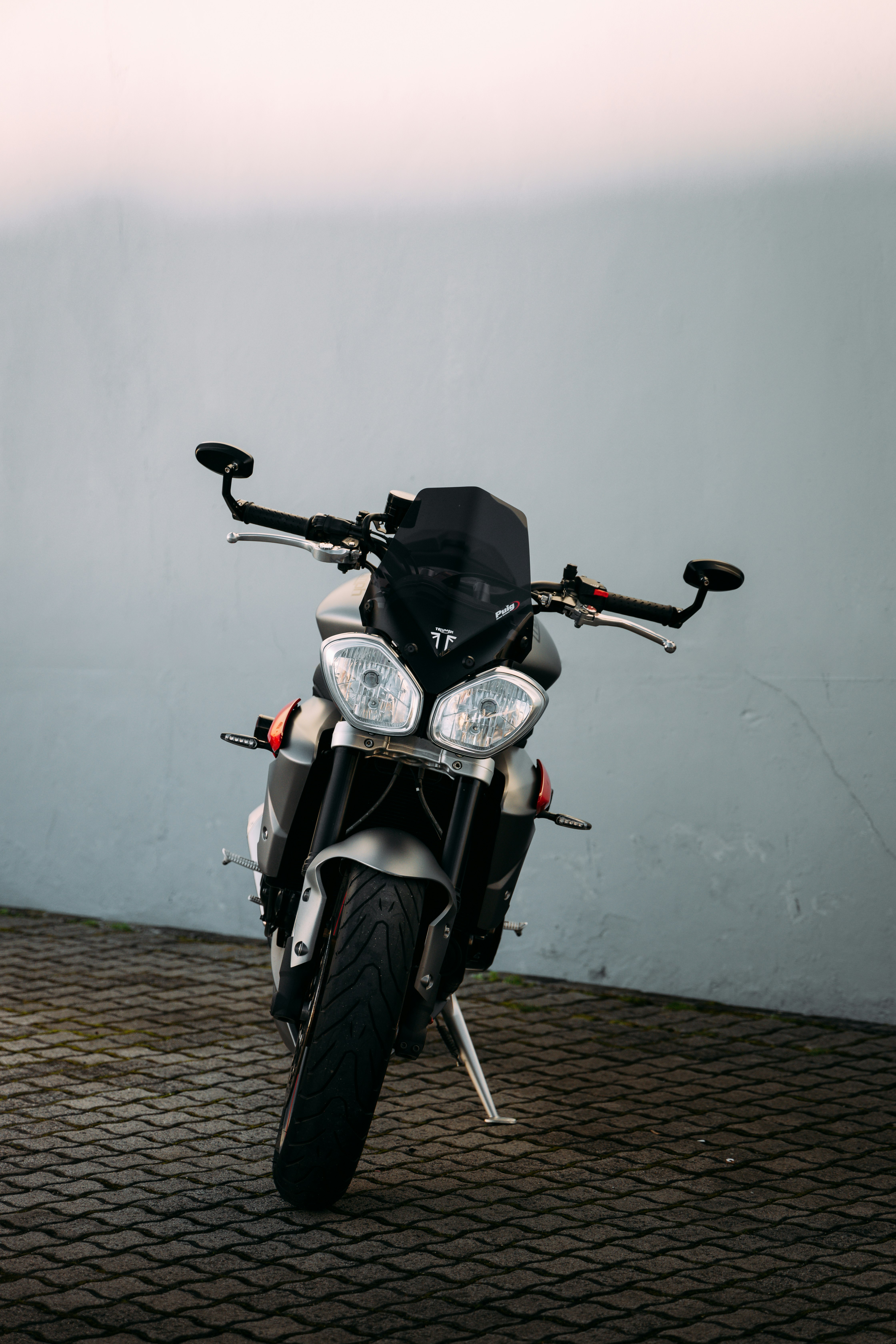 black and silver motorcycle parked beside white wall
