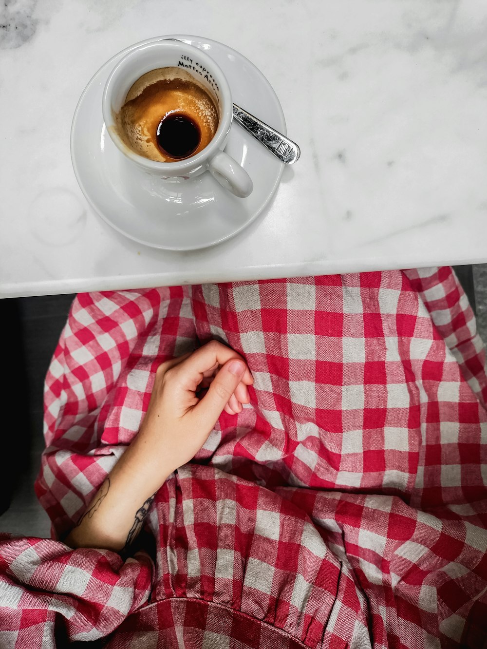 person holding white ceramic cup with saucer