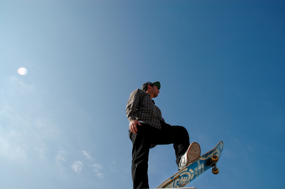 man in black and white checkered dress shirt and black pants standing on skateboard during daytime