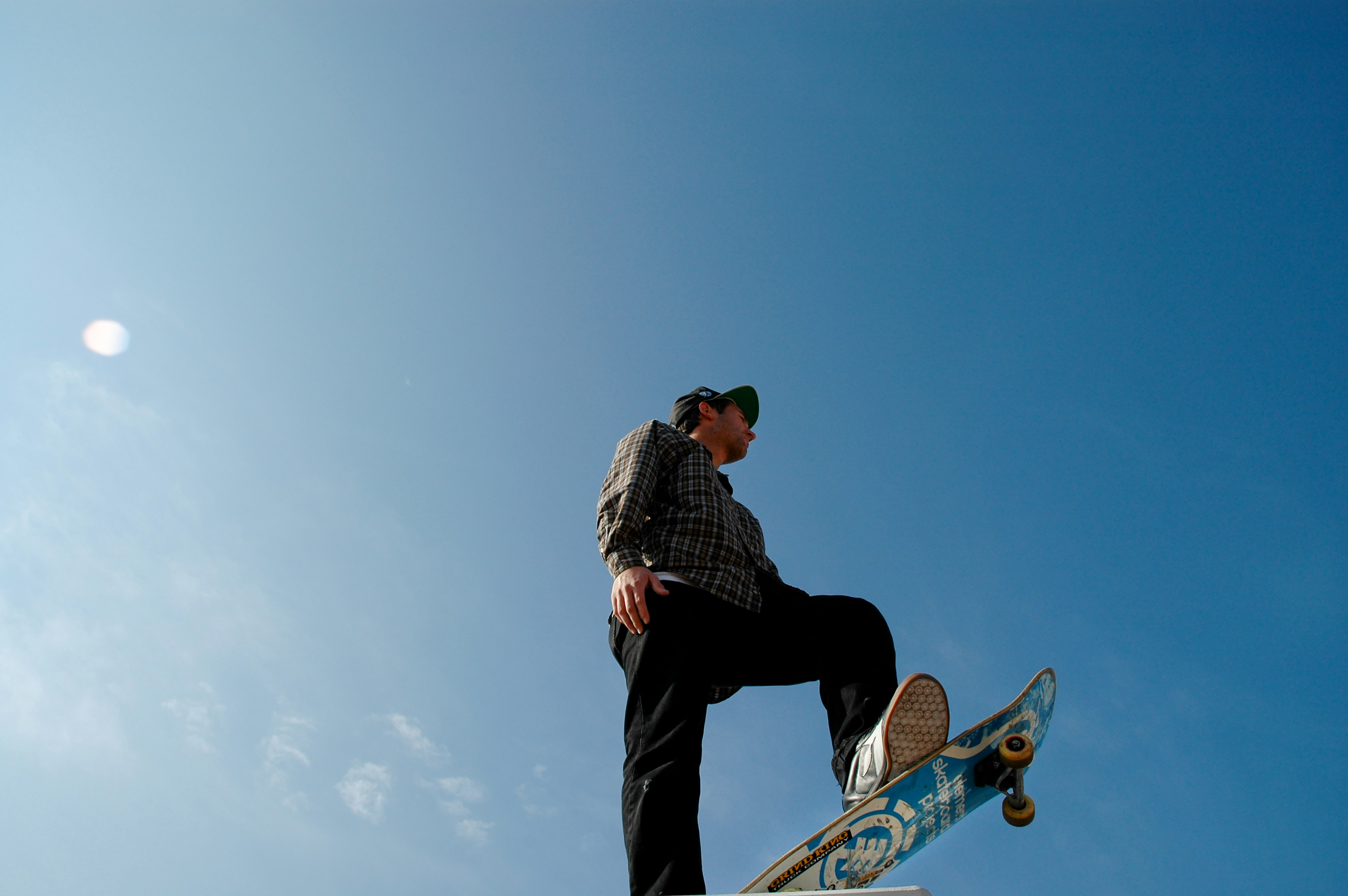 man in black and white checkered dress shirt and black pants standing on skateboard during daytime