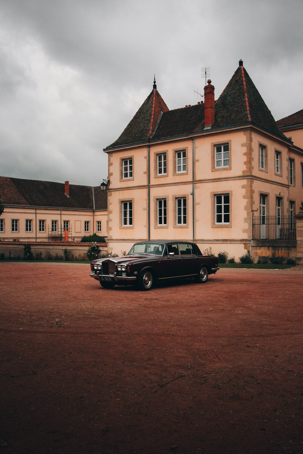 black sedan parked beside brown concrete building during daytime