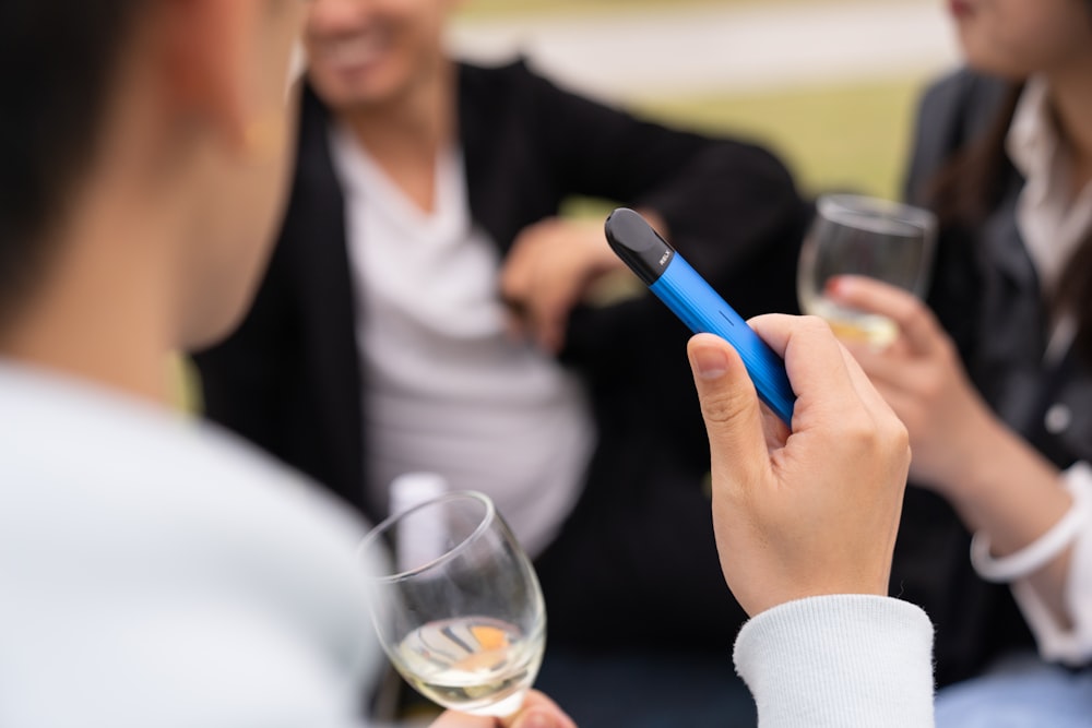 woman in white long sleeve shirt holding blue pen