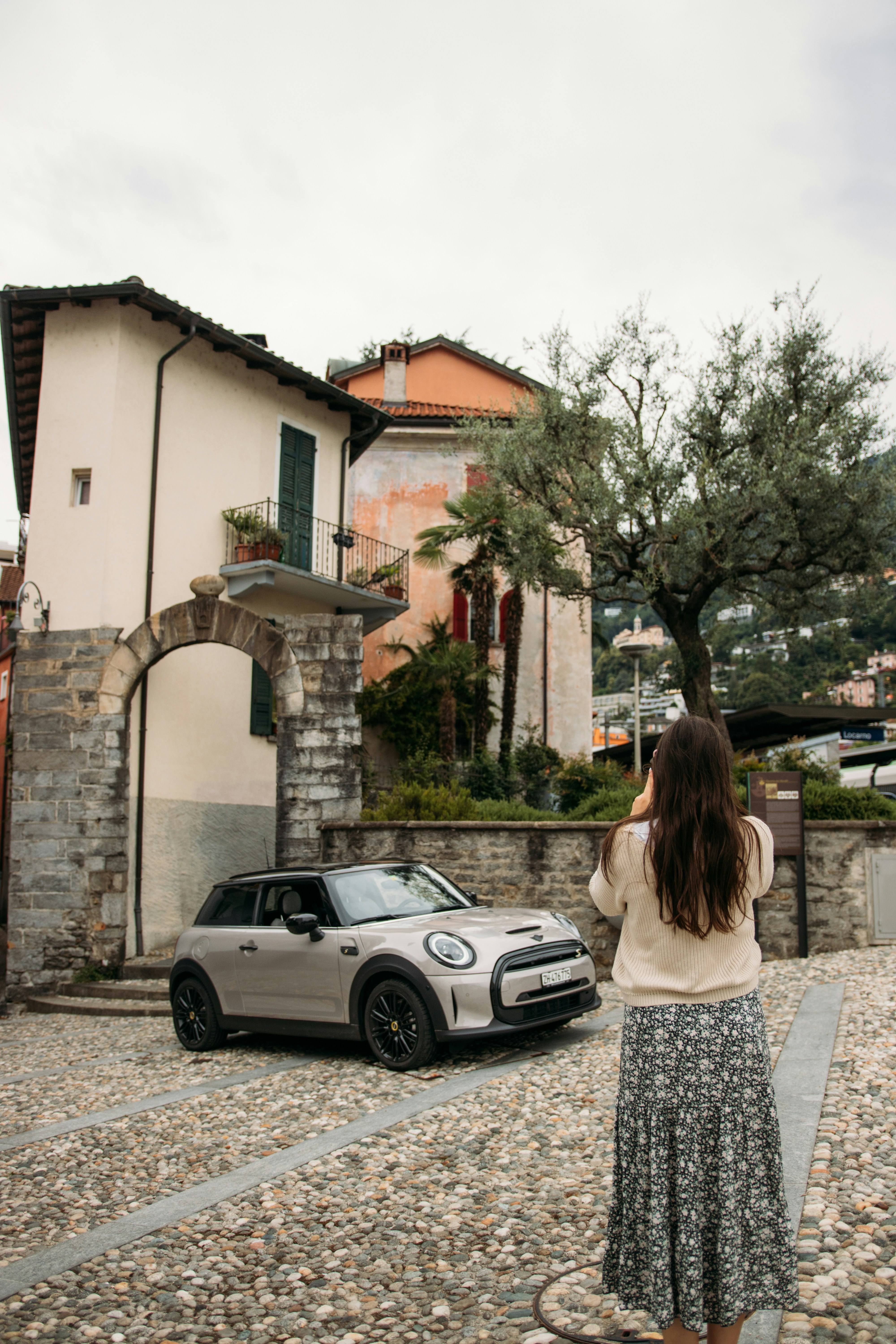 woman in white and black floral dress standing near white car during daytime