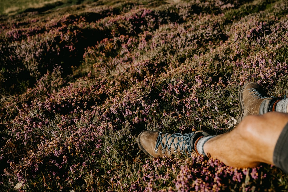 Persona con zapatos marrones y blancos con cordones de pie en un campo de hierba verde durante el día