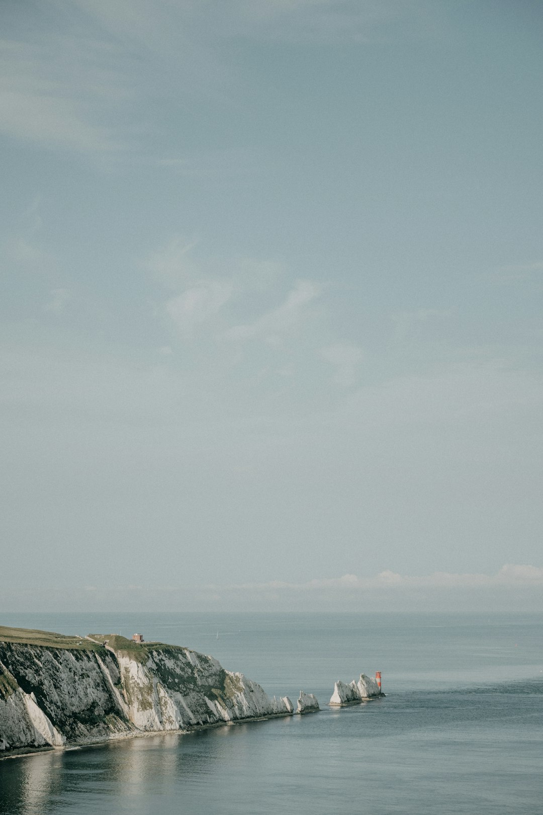 person in red shirt standing on rock formation near sea during daytime