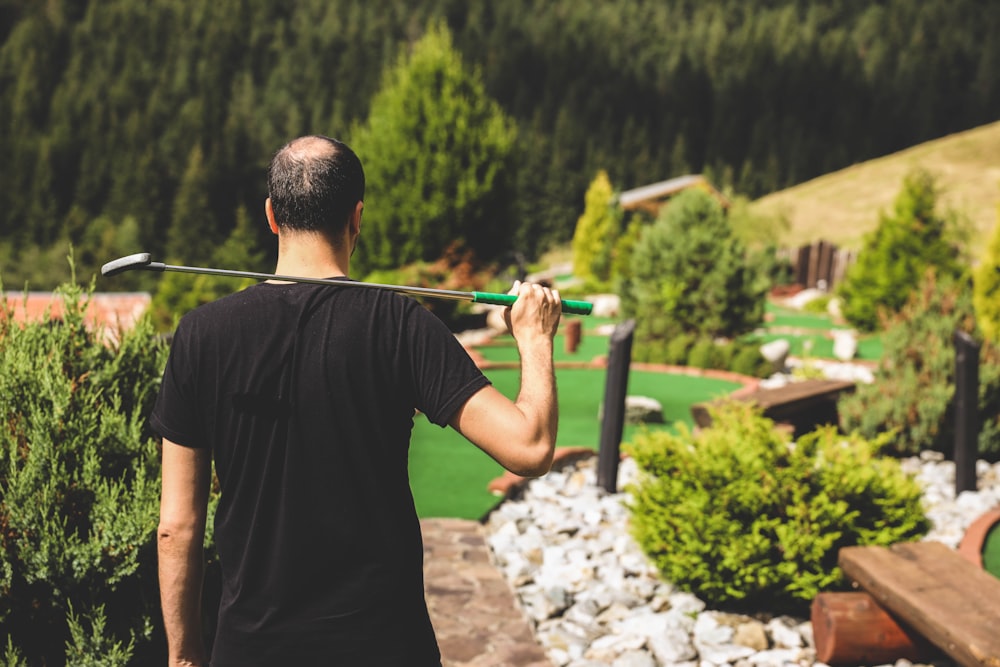 man in black crew neck t-shirt holding gray metal rod during daytime