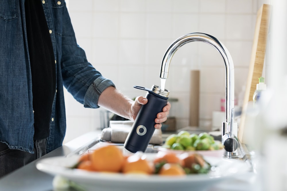 person holding stainless steel faucet