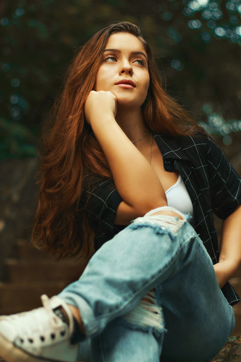 woman in black shirt and blue denim jeans sitting on brown wooden bench