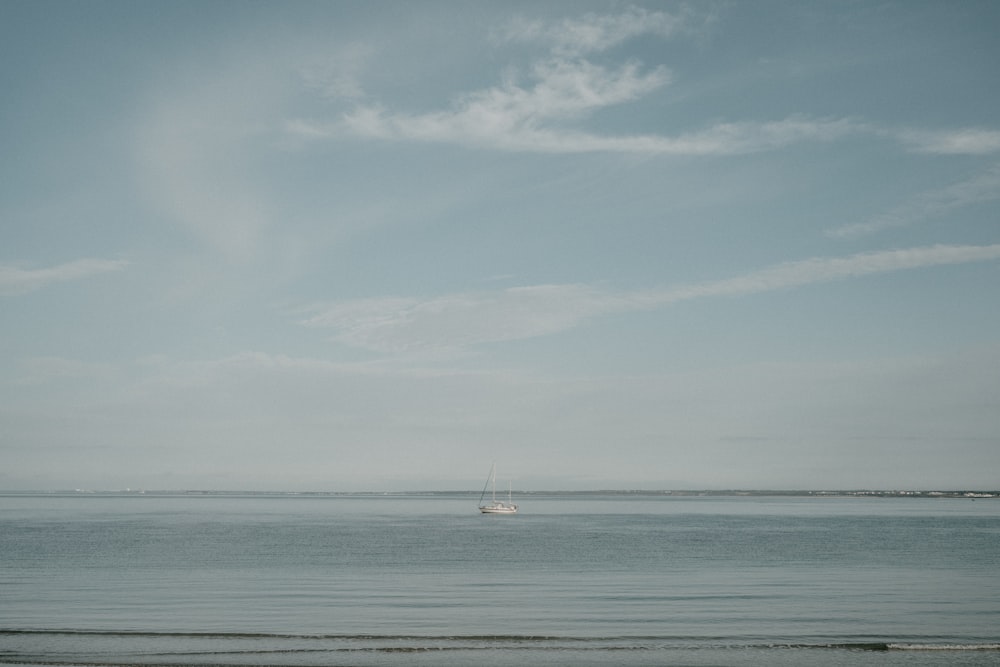 velero blanco en el mar bajo nubes blancas y cielo azul durante el día